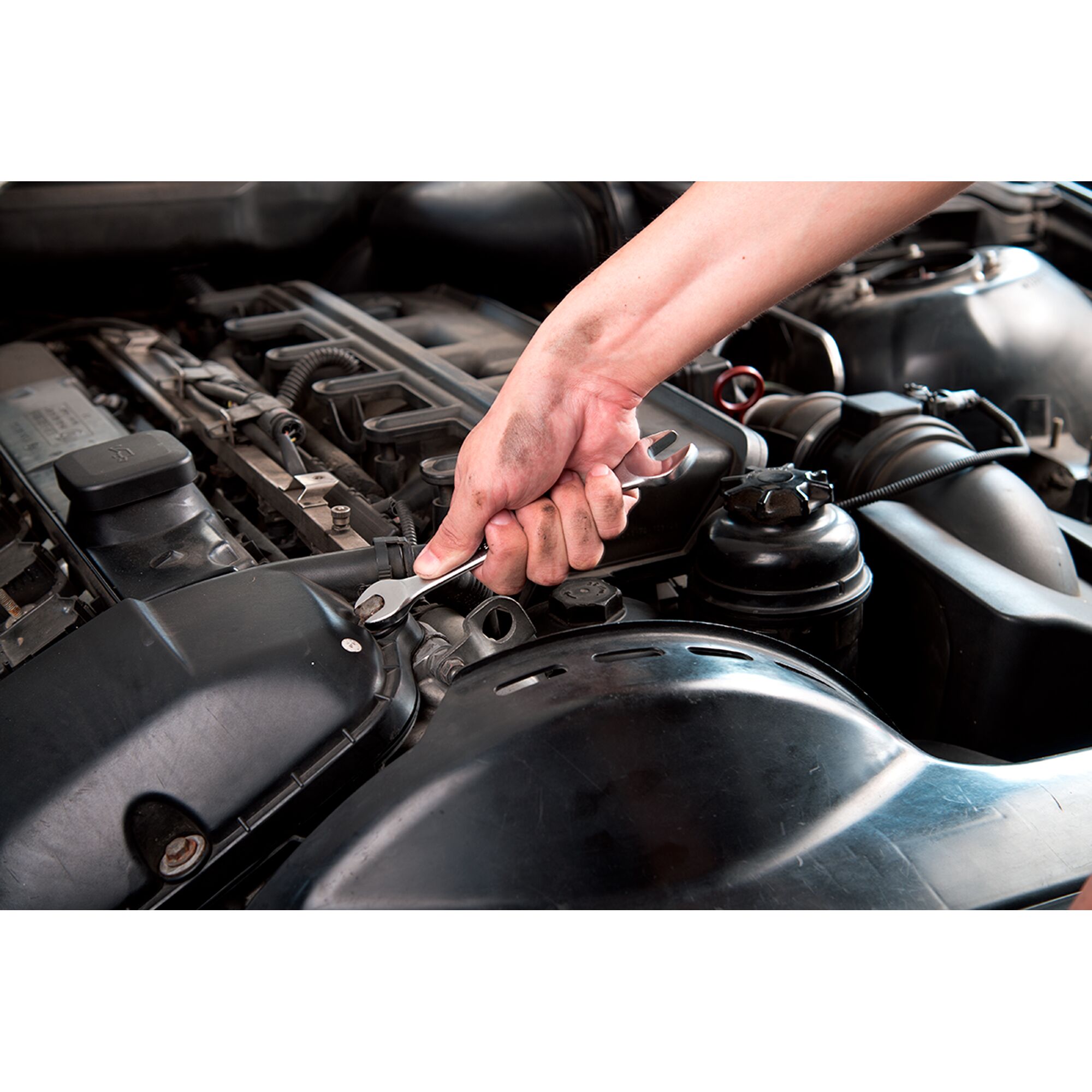 STANLEY STMT23119_BasicWrench used to tighten a bolt on a car engine, close-up view of hand and tool.