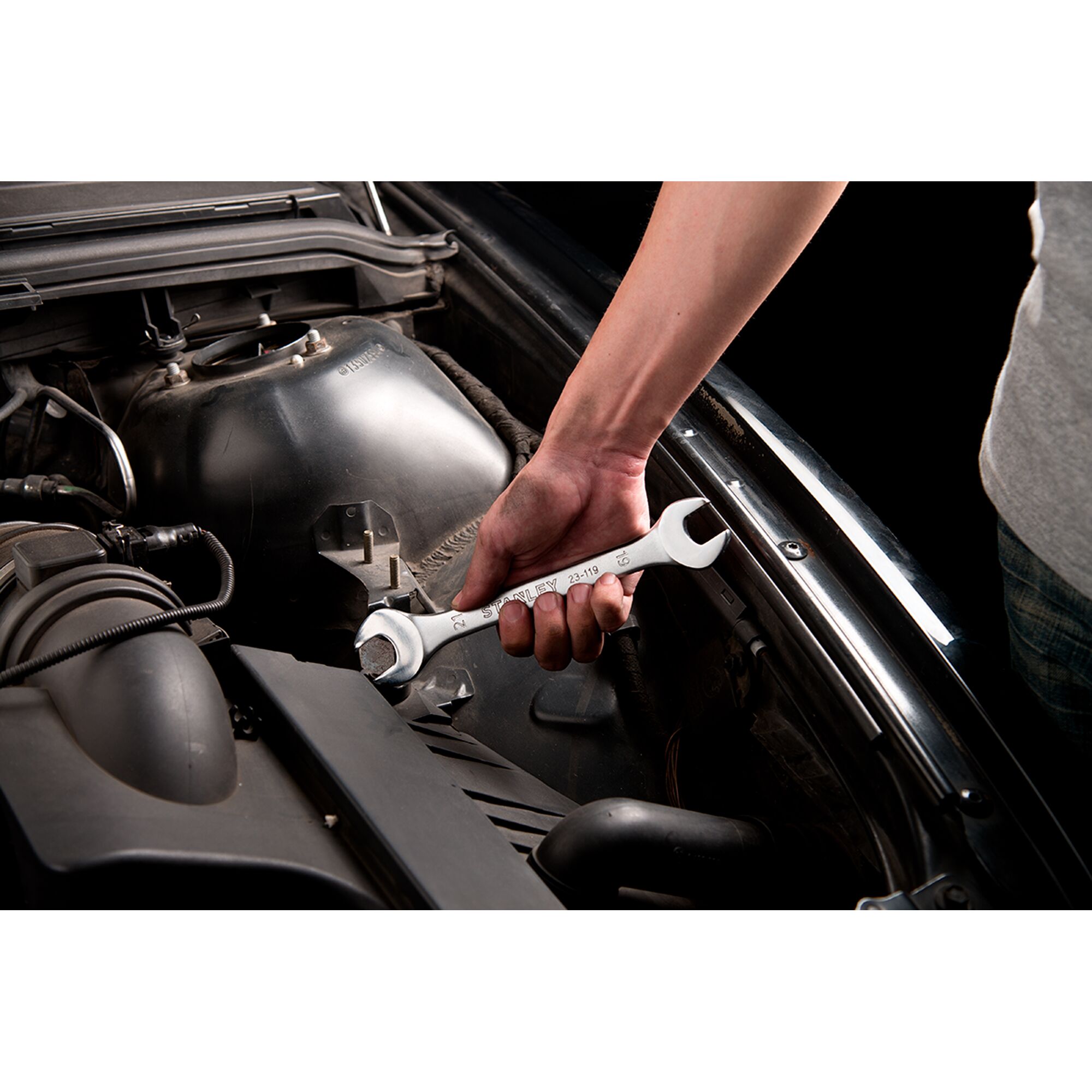 STANLEY STMT23119_BasicWrench wrench being used to tighten a bolt in a car engine compartment.